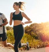 At Hyde Park Physiotherapy we help to keep active professionals moving! Photo showing a happy young couple running outdoors in bright sunshine.