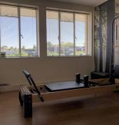 The Hyde Park Physiotherapy Pilates Rehabilitation Area. Photo showing a Pilates Reformer in a bright room, against a wall with a forest scene wallpapered on it.