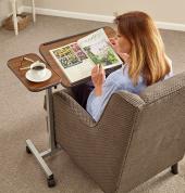 Lady happily reading a magazine and having coffee in a chair with the help or assistance of an adjustable overbed table